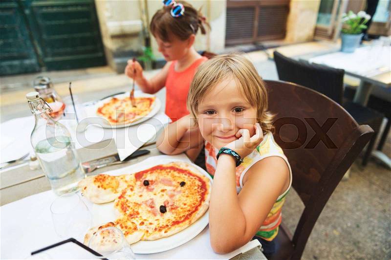 Happy little boy eating kid\'s pizza in the restaurant. Menu for children, animal shaped italian pizza for youngsters, stock photo