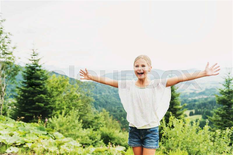 Little kid girl hiking in mountains, arms up wide open. Image taken in canton of Vaud, Switzerland, stock photo
