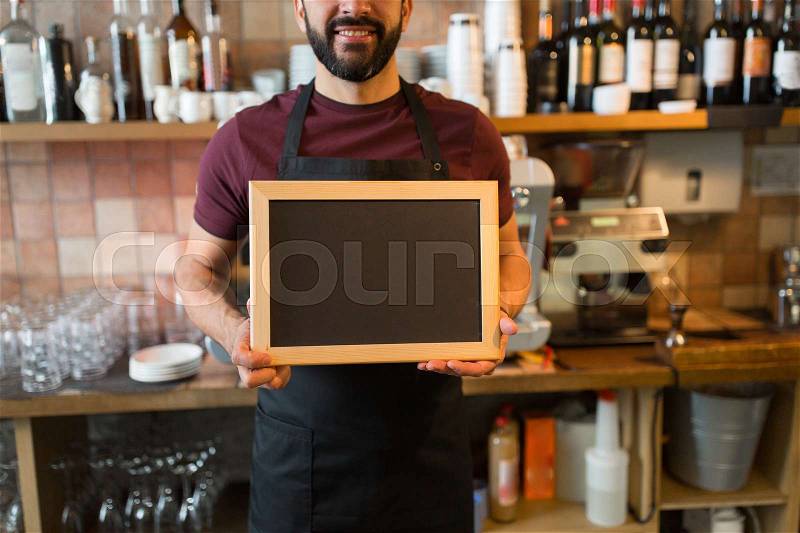 Small business, people and service concept - happy man or waiter with blank blackboard at bar, stock photo