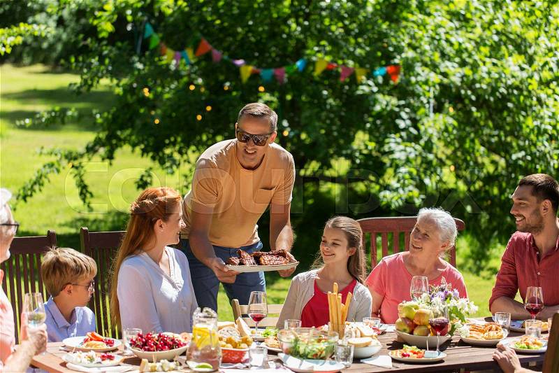 Leisure, holidays and people concept - happy family having festive dinner or summer garden party, stock photo