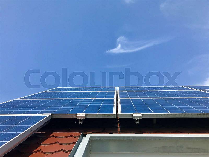 House roof with solar panels on top against great blue sky, stock photo