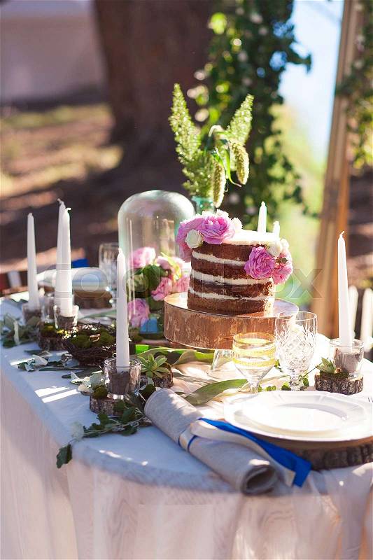 Puffy wedding cake with flowers on decor table with candles, stock photo