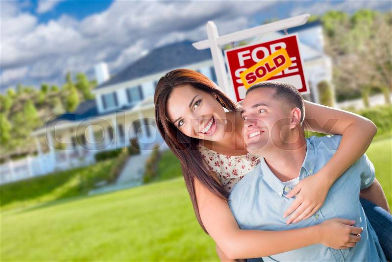Playful Excited Military Couple In Front of Home with Sold Real Estate Sign, stock photo