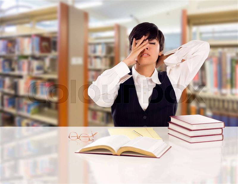 Young Female Mixed Race Student Stressed and Frustrated In Library with Blank Pad of Paper and Books, stock photo