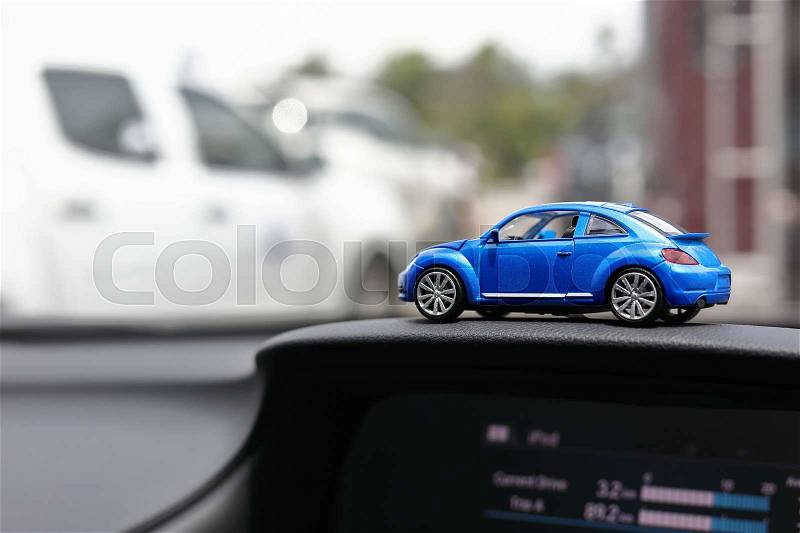 Blue toy small vehicle on car console with traffic jam in city background, stock photo