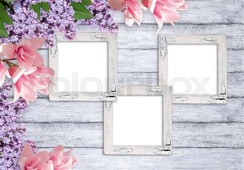 Three retro empty photo frames with magnolia and lilacs flowers on background of shabby wooden planks in rustic style, stock photo