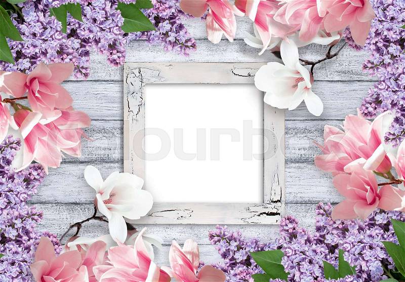 Retro empty photo frame with magnolia and lilacs flowers on background of shabby wooden planks in rustic style, stock photo