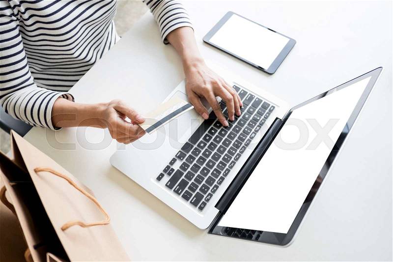 Closeup of happy young woman holding credit card inputting card information while and using laptop computer at home. Online shopping concept, stock photo