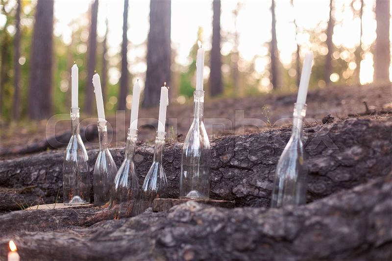 Wedding decorations in rustic style. Outing ceremony. Wedding in nature. Burning candles in bottles in forest, stock photo