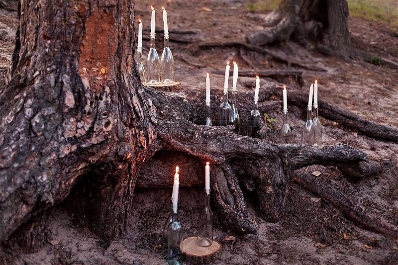 Wedding decorations in rustic style. Outing ceremony. Wedding in nature. Burning candles in bottles in forest, stock photo