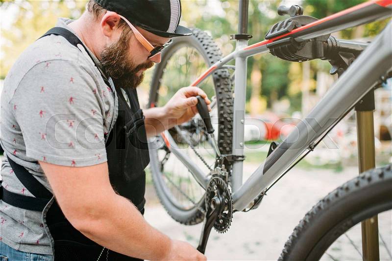 Bicycle mechanic repair front speed shifter. Cycle workshop outdoor. Bike fixing on stand, stock photo