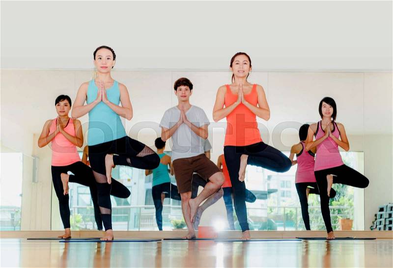 Yoga class in studio room,Group of people doing tree pose and namaste with calm relax emotion,Meditation pose,Wellness and Healthy Lifestyle, stock photo
