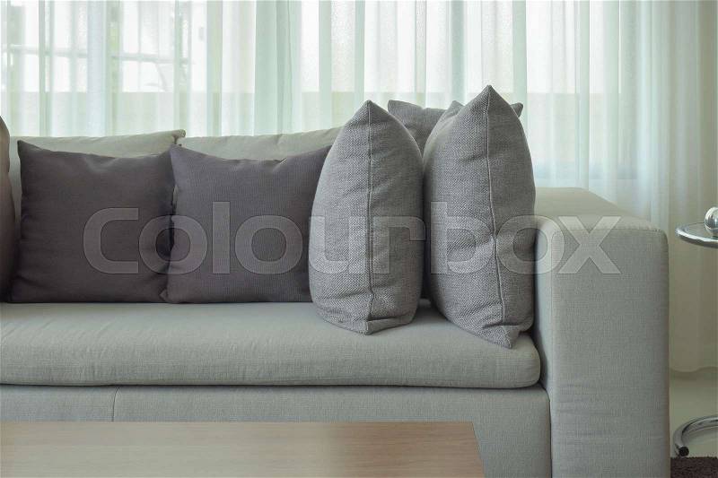 Gray pillows on beige color sofa with sheer in background, stock photo