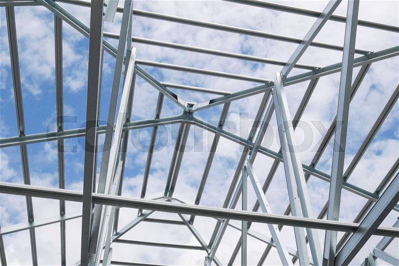 Structure of steel roof frame with blue sky and clouds at construction site, stock photo