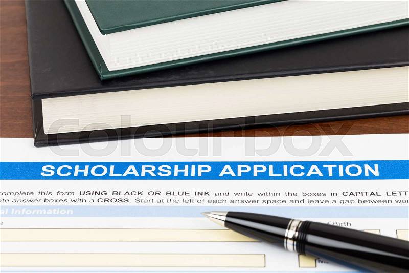 Scholarship application form with pen and text book; the document is mocked-up, stock photo