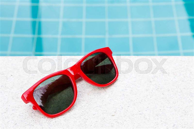 Red sun glasses near swimming pool outdoor, stock photo