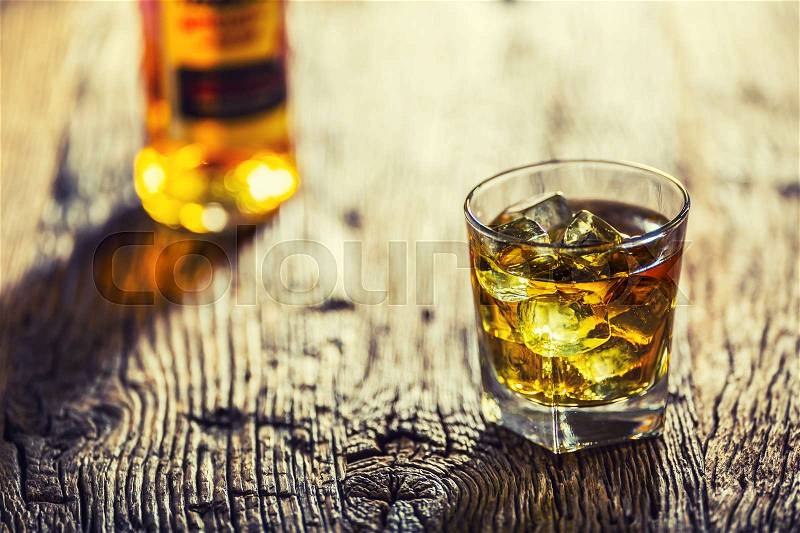Whiskey. Whiskey drink with ice cubes on old rustic oak table, stock photo