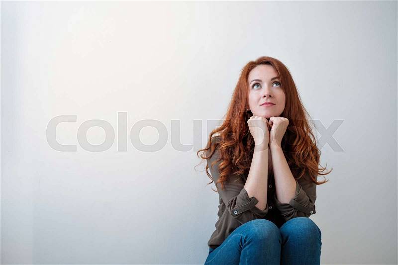 Portrait of a beautiful young woman with long read hair thinking, isolated on white background. Looking up and dream, stock photo