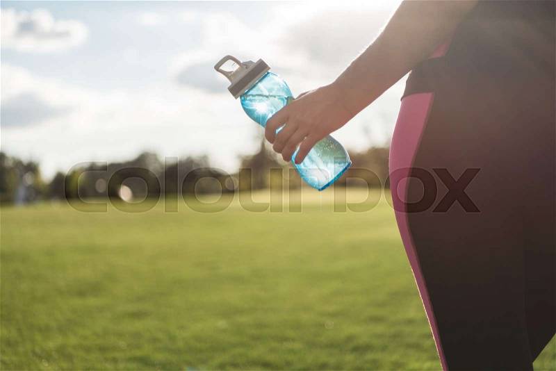 Partial view of woman holding water bottle, stock photo