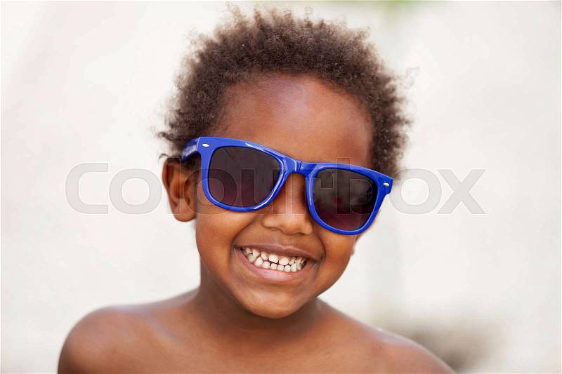 Funny Afro-American kid with blue sunglasses and a beautiful smile, stock photo