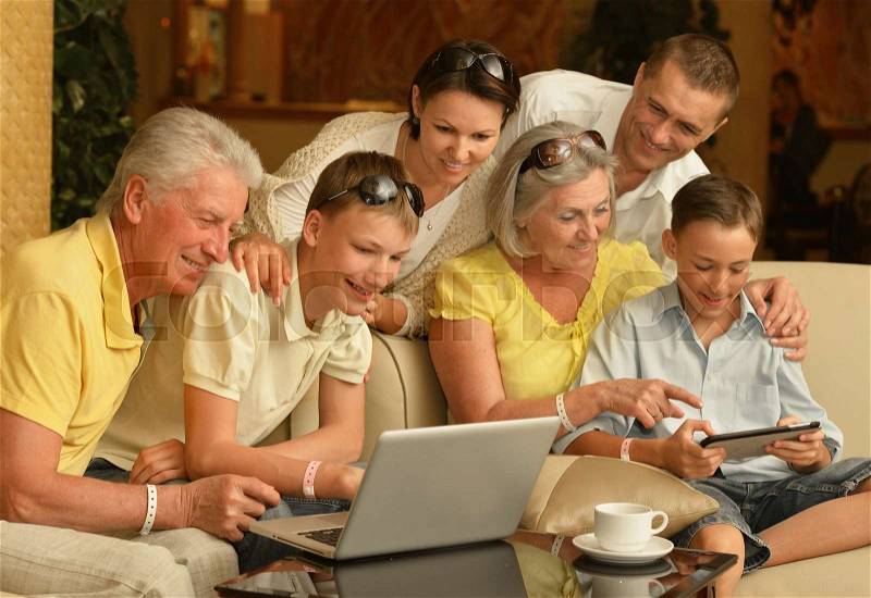 Portrait of big happy family sitting on couch with digital devices, stock photo