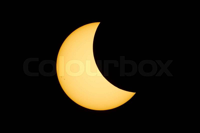 The sun, with a prominent group of sunspots is partially covered by the moon during the total solar eclipse in August, 2017, stock photo