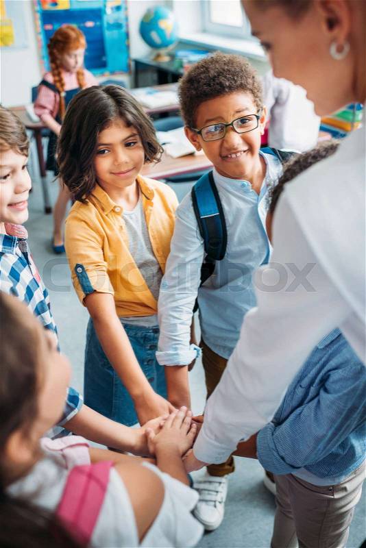 Beautiful young teacher and pupils making team sign at school, stock photo