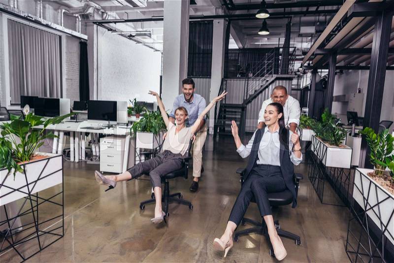 Excited young business people on chairs having fun together in office , stock photo