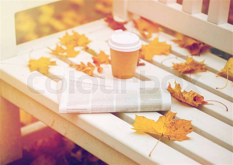 Season and news concept - newspaper and coffee cup on bench in autumn park, stock photo