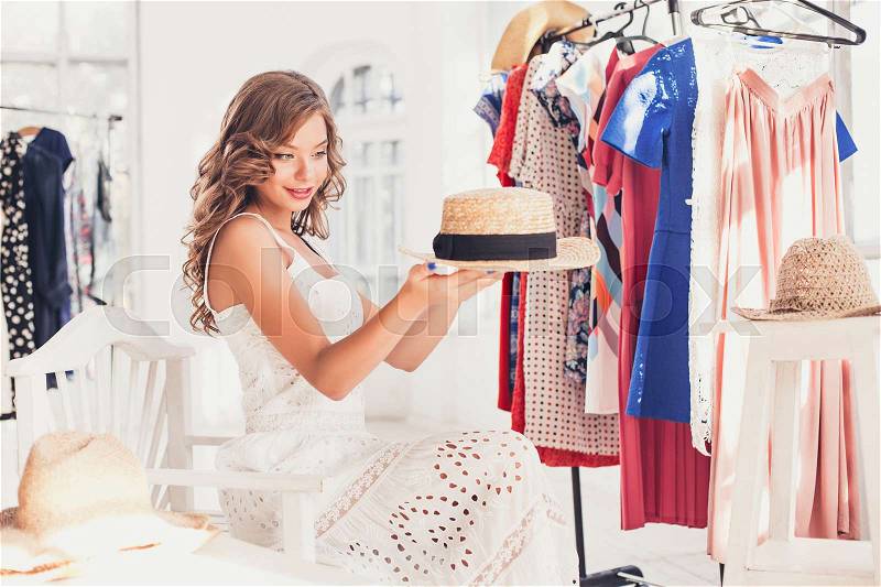 Attractive woman trying on a hat. Happy summer shopping concept, stock photo