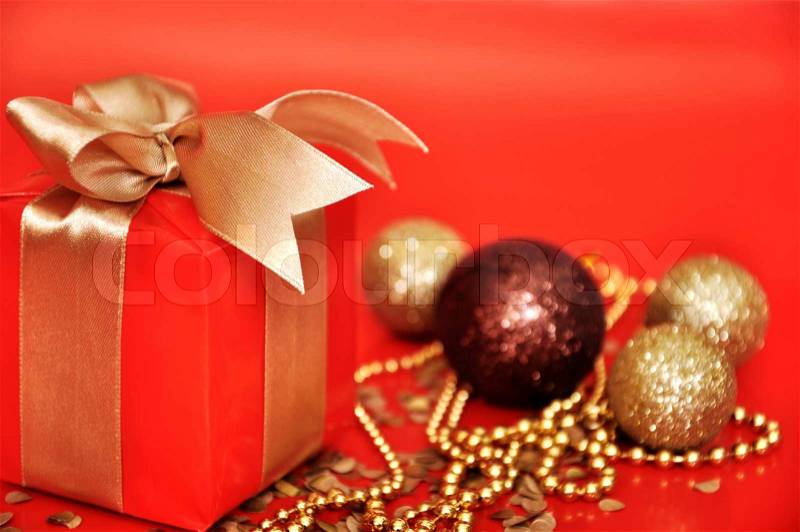 Red gift box with golden ribbon and cristmas decoration on red background close-up, stock photo