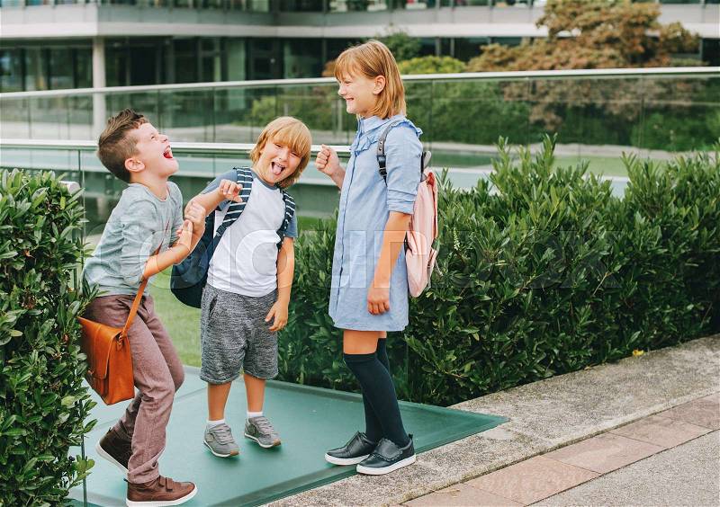 Group of 3 kids playing Rock, Paper, Scissors game on schoolyard. Back to school concept, fashion for children, stock photo