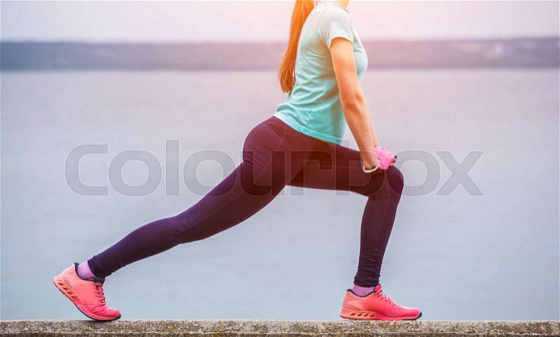 Young, attractive, athletic girl in a sports suit, engaged in morning sports training on the background of the lake, stock photo