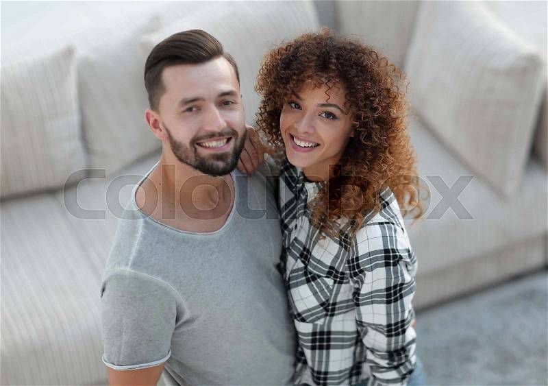 Young couple standing in new living room and looking at camera, stock photo