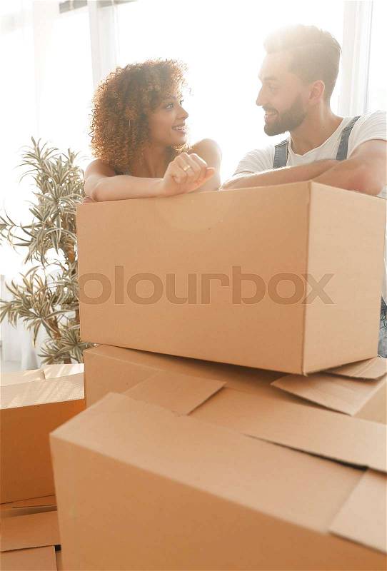 Happy couple standing near boxes in their new apartment. The concept of moving, stock photo