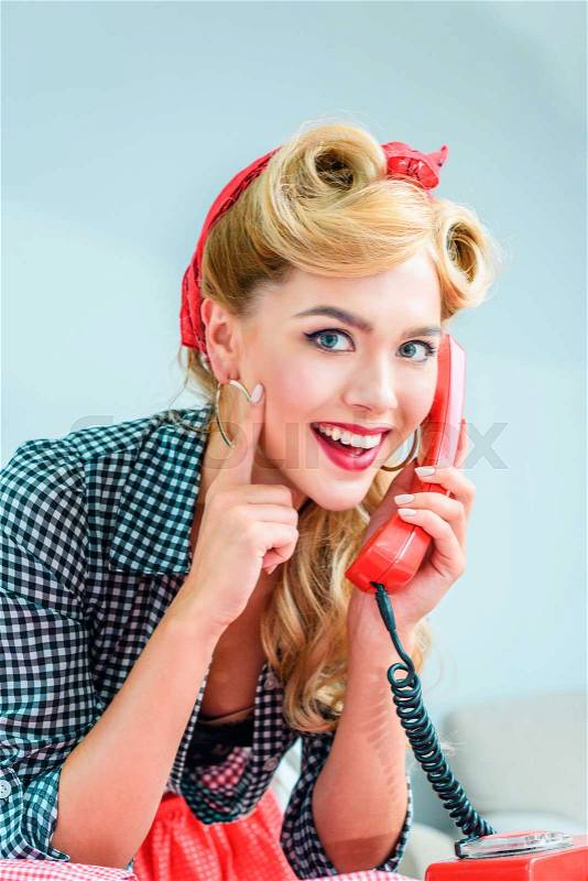 Beautiful smiling pin up girl talking on vintage telephone , stock photo