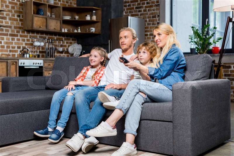Smiling young family with two children watching tv together , stock photo