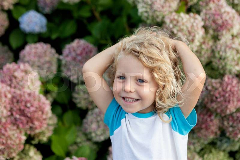 Cute small child with many flowers in the garden, stock photo