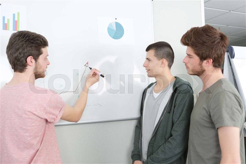 Group presenting and writing on whiteboard, stock photo