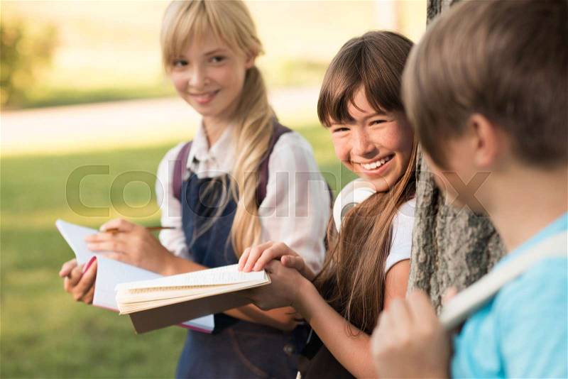 Attractive smiling teenage girls studying together in park, stock photo