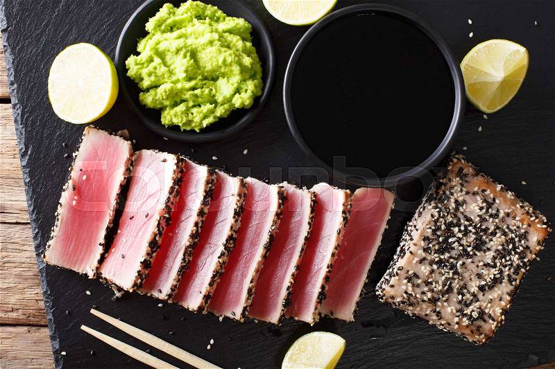 Fresh tuna meat in sesame and soy sauce, wasabi, lime closeup on the table. Top view from above horizontal , stock photo