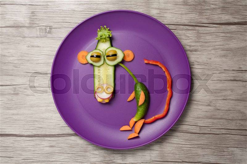 Funny vegetable monkey on purple plate and table, stock photo