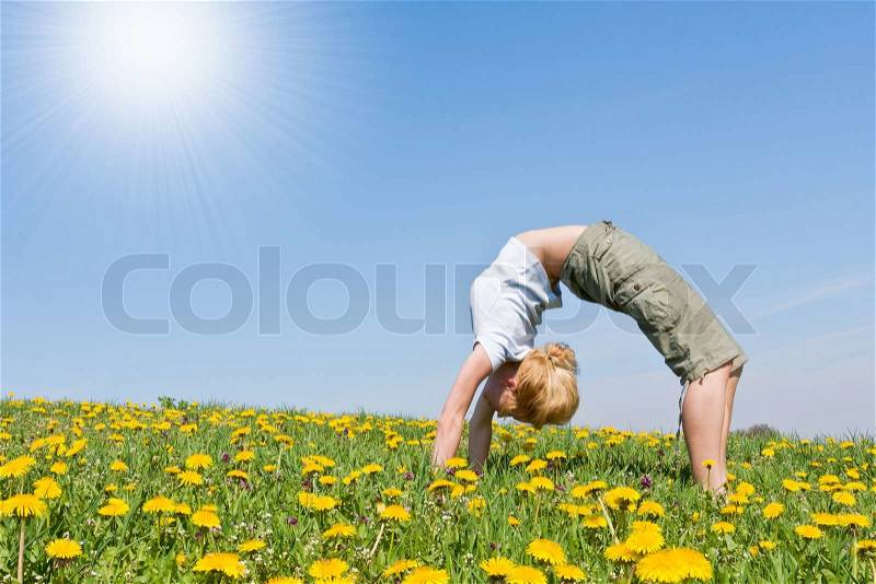 Young female excercising yoga on flowery meadow, stock photo