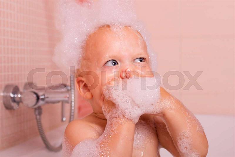 Funny toddler in a foam taking a bath and looking up, stock photo