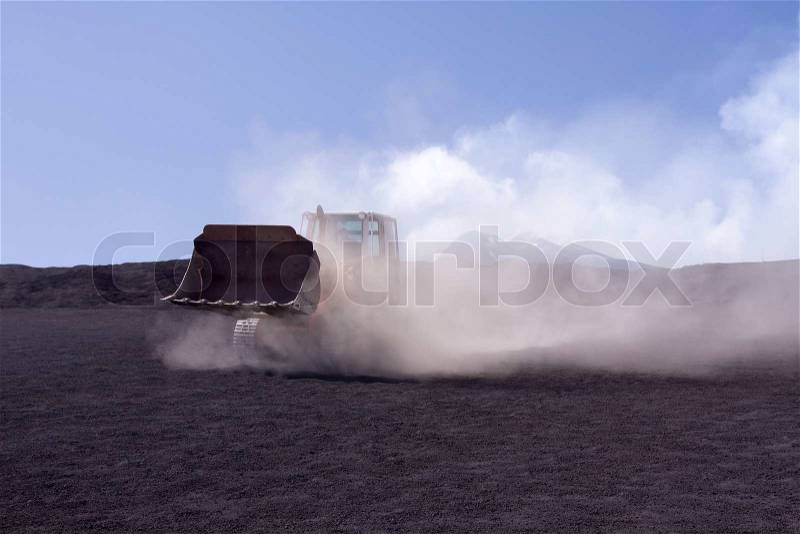 Bulldozer during work covered in dust clouds, stock photo