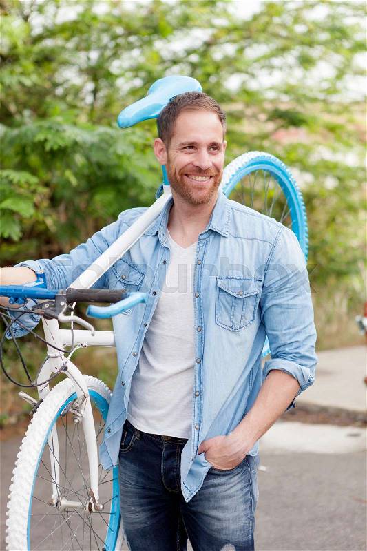 Handsome man with denim clothes enjoying with his bike in the park, stock photo