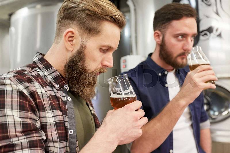 Production, manufacture, business and people concept - men testing and drinking non-alcoholic or craft beer at brewery, stock photo
