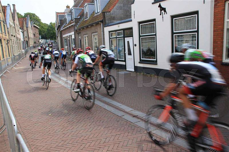 The group of cyclists are going up the hillock in one of the streets in the village Zuidland on a sunny day in the summer, stock photo