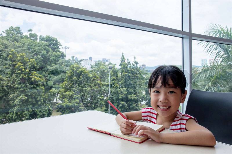 Asian little Chinese girl writing homework at home, stock photo
