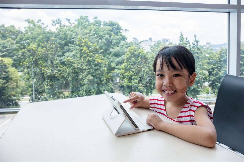 Asian Chinese little girl playing tablet computer at home, stock photo